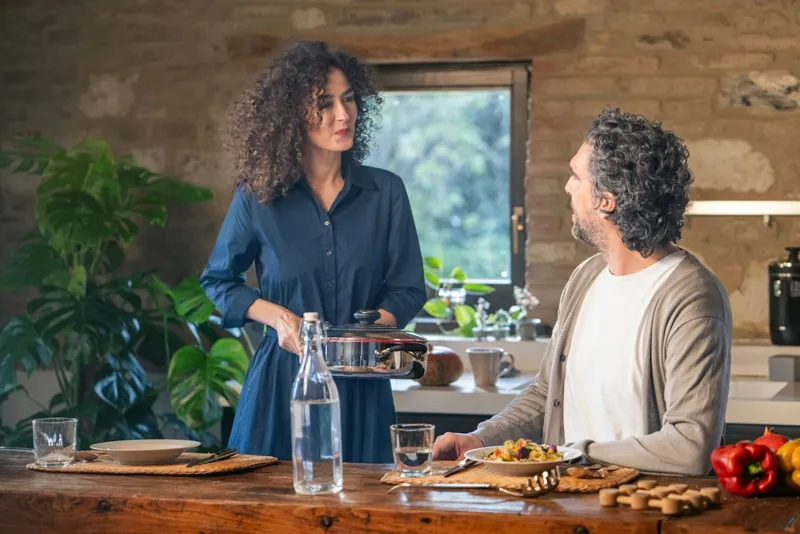 Couple sharing a meal they cooked together at a wood counter in a warm stone-walled kitchen